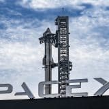Starship stacked behind a SpaceX sign