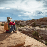 Hiker sitting on red rocks with a phone