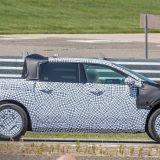 Ford Fathom electric pickup in black and white camouflage wrap beside a highway guardrail