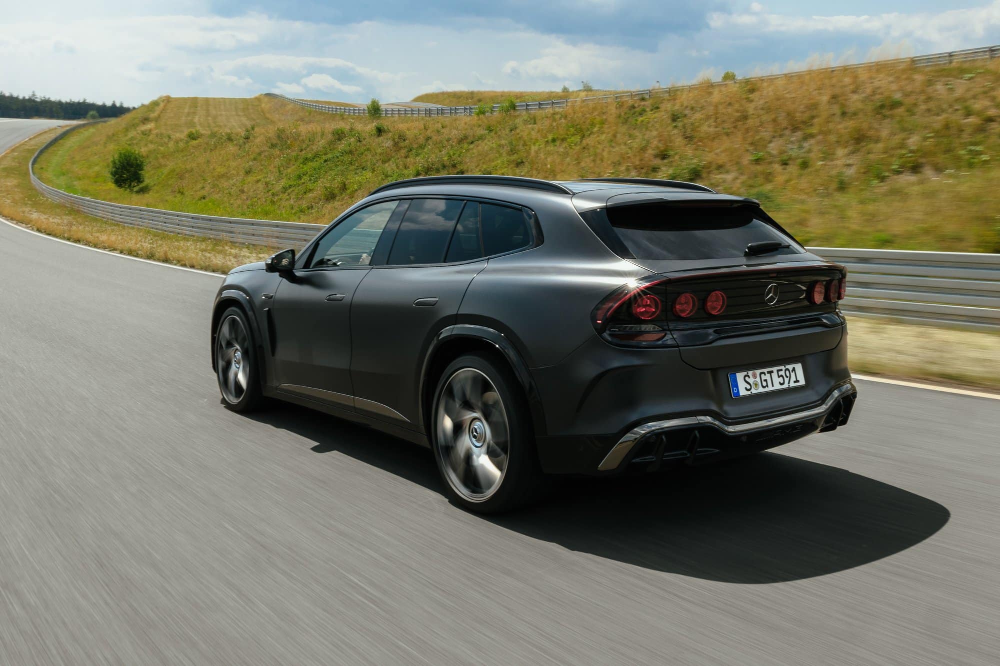 Grey Mercedes-AMG GT 55 SUV driving on a test track, rear three-quarter view showing round taillights