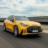 Yellow Mercedes-AMG GT 63 SUV driving on a test track, front three-quarter view