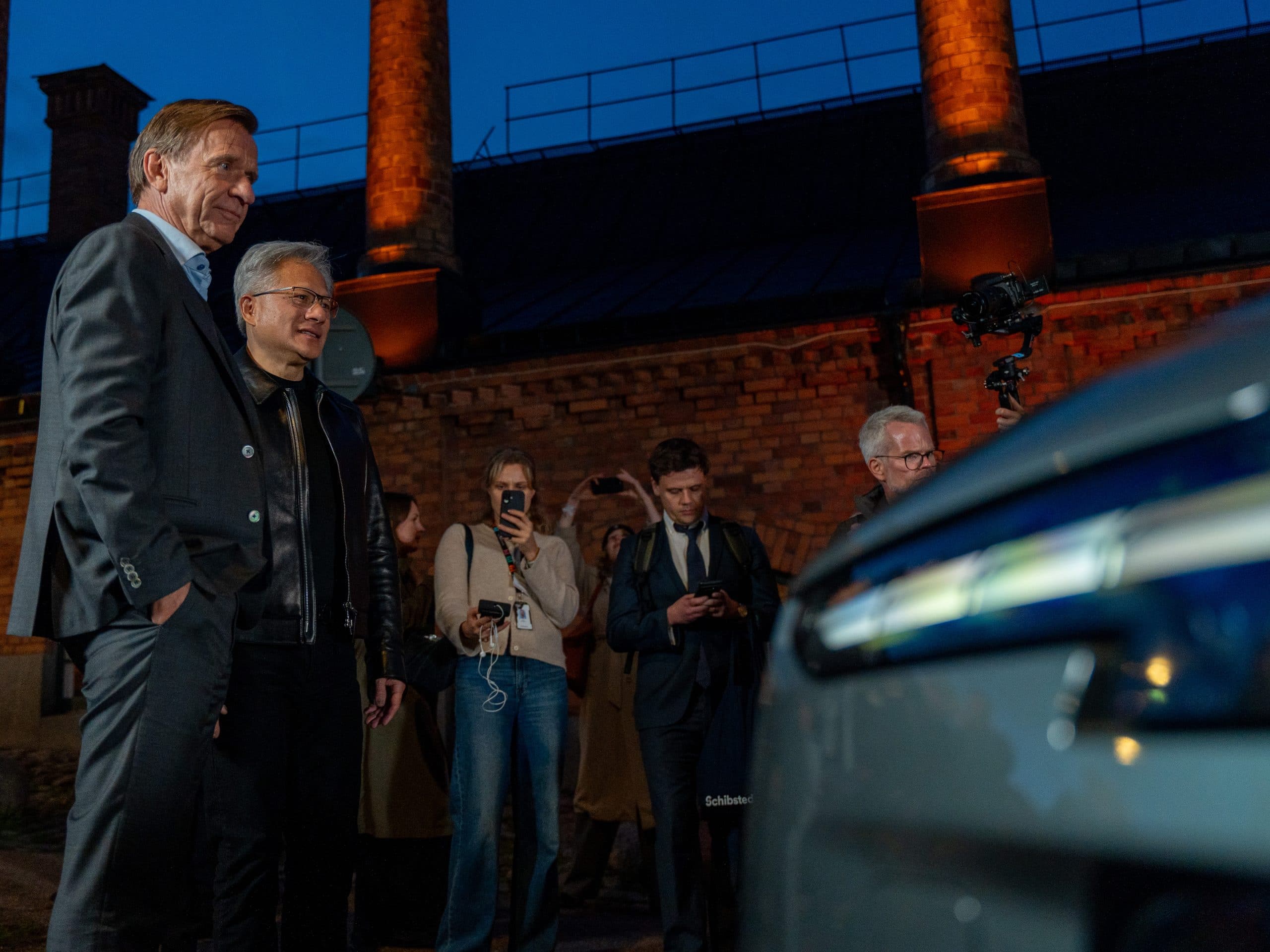 Håkan Samuelsson and Jensen Huang beside a dark Volvo as media gather at the partnership announcement
