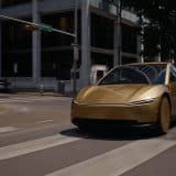 Gold Tesla Cybercab driving through a downtown Austin intersection