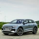 Audi Q4 e-tron in Geyser blue parked in front of wind turbines