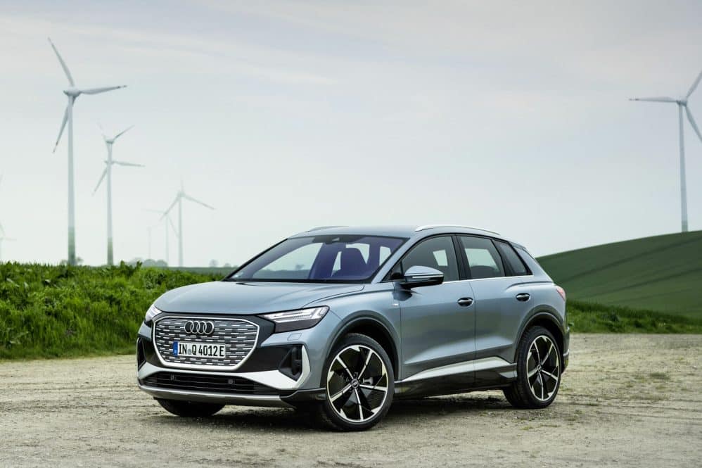 Audi Q4 e-tron in Geyser blue parked in front of wind turbines
