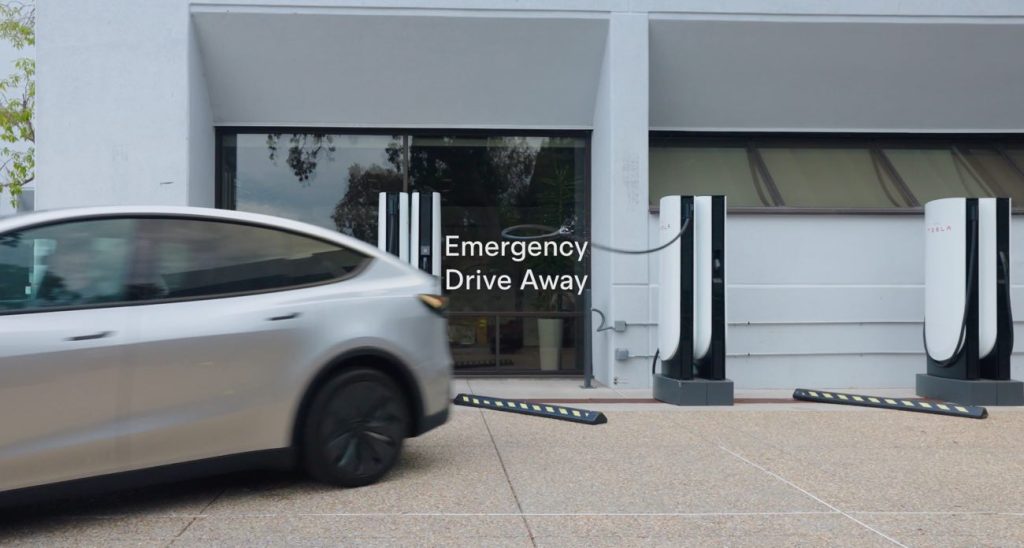 Silver Tesla Model Y pulling away from Superchargers in front of a building, with Emergency Drive Away text overlay