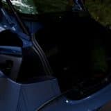 A Tesla Mobile Connector cable plugged into a blue Tesla's charge port beside an open trunk