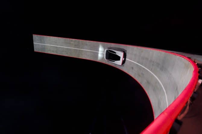 Overhead view of the white Tesla Roadster driving on a red-edged banked track