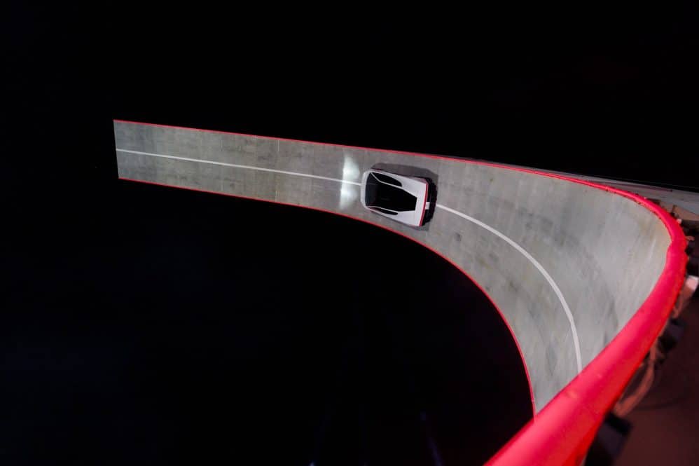 Overhead view of the white Tesla Roadster driving on a red-edged banked track