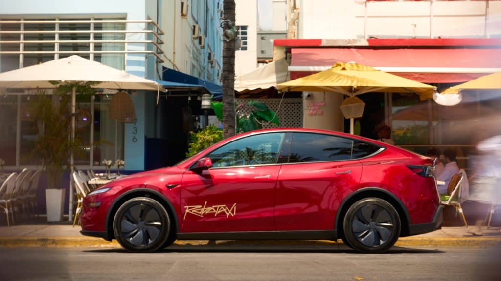 Red Tesla Robotaxi Model Y parked outside Art Deco cafes in Miami