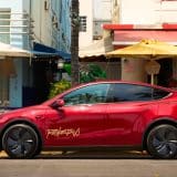 Red Tesla Robotaxi Model Y parked outside Art Deco cafes in Miami
