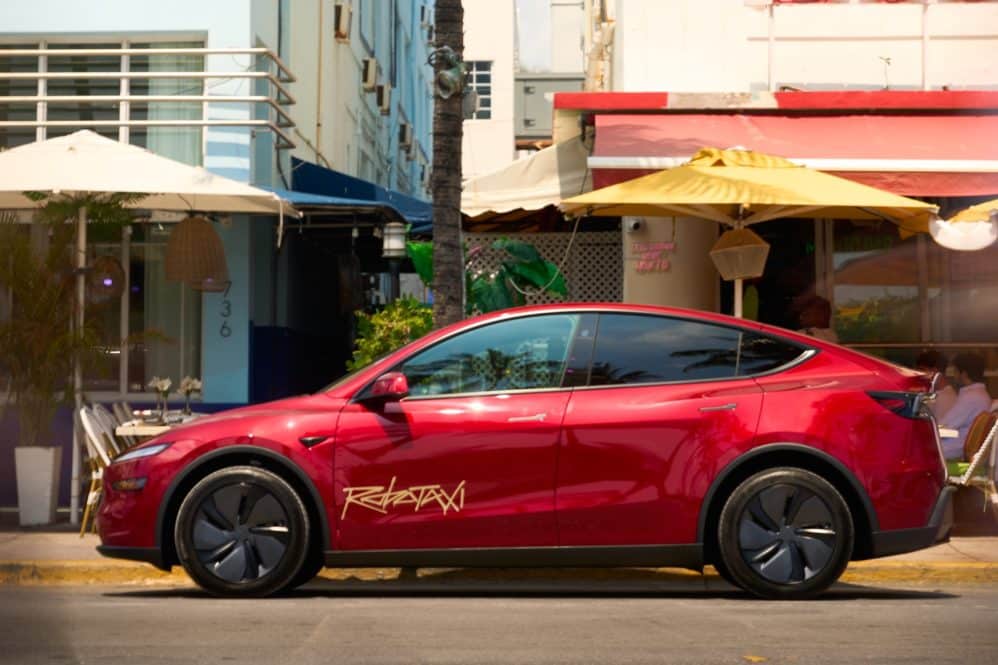 Red Tesla Robotaxi Model Y parked outside Art Deco cafes in Miami