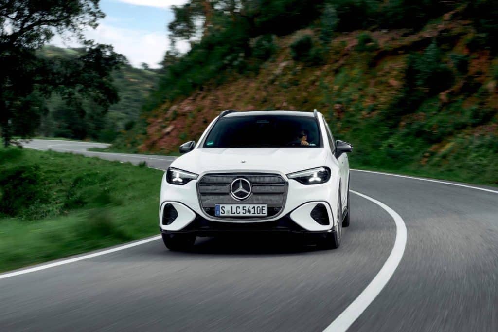 White Mercedes-Benz electric GLC cornering on a winding hillside road