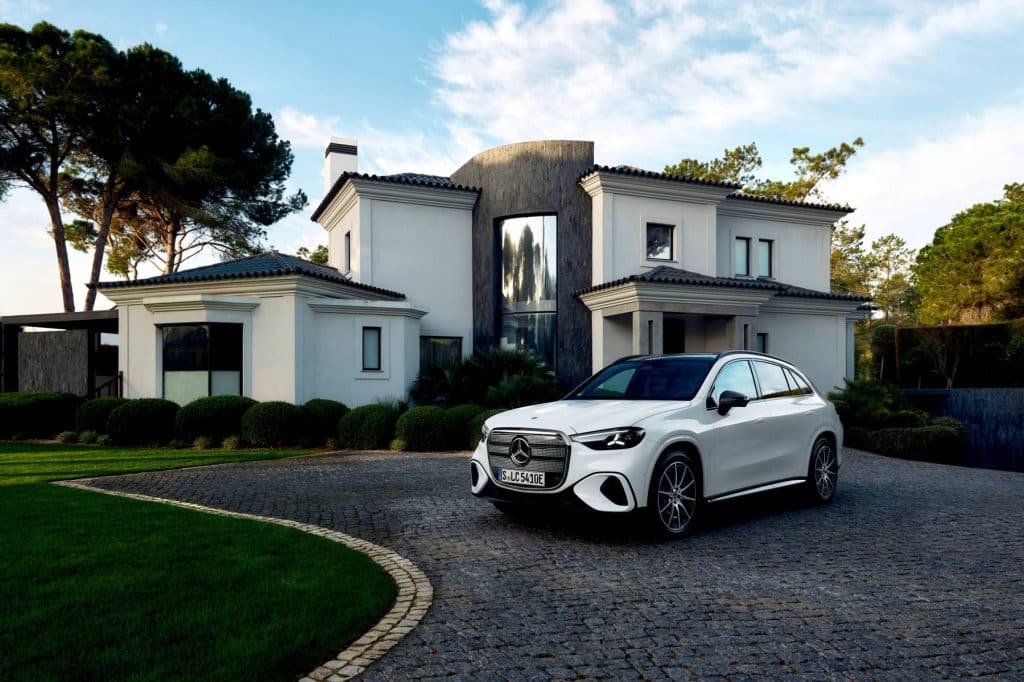 White Mercedes-Benz electric GLC parked on a cobblestone driveway in front of a villa