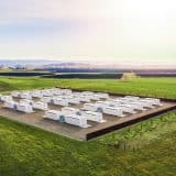 Rows of Tesla Megapack battery units at an energy storage site in a green field