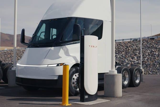 Tesla Semi parked between two Tesla Megacharger posts at a charging site
