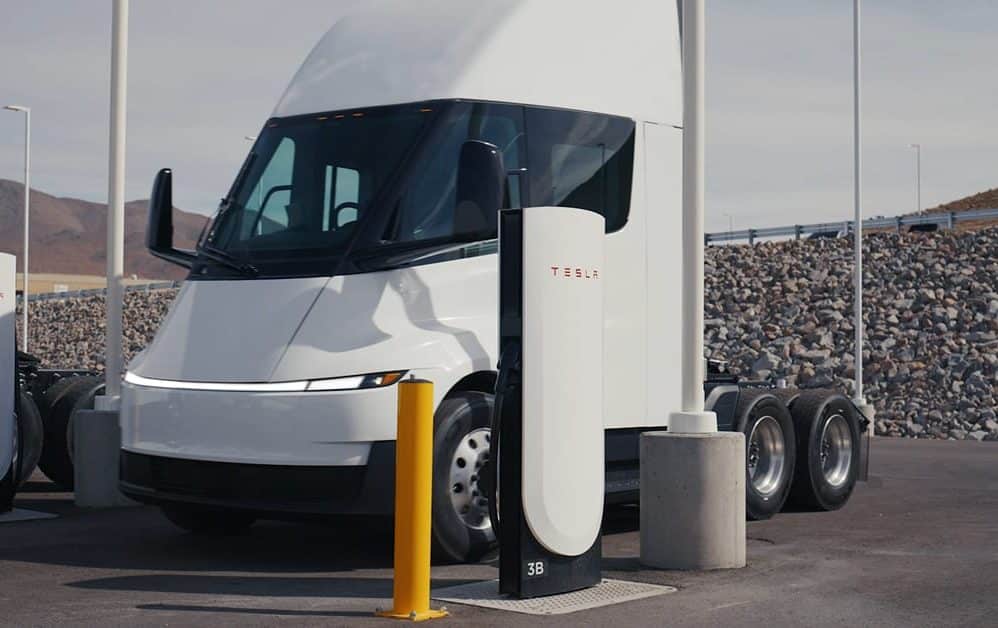 Tesla Semi parked between two Tesla Megacharger posts at a charging site