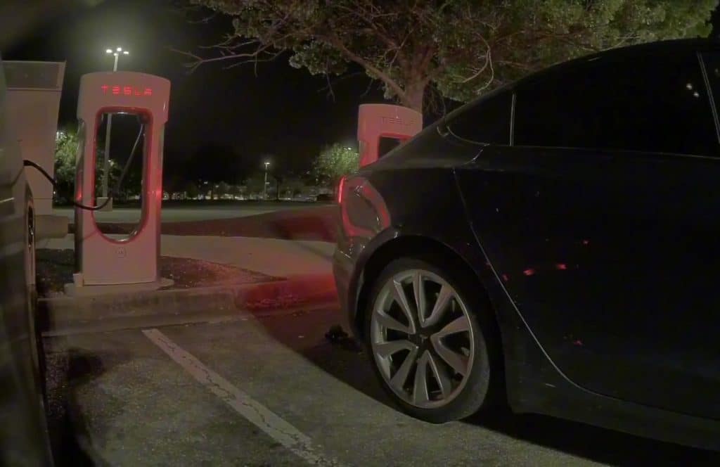 Tesla Model 3 pulling away from a Supercharger stall at night after Emergency Drive Away activation
