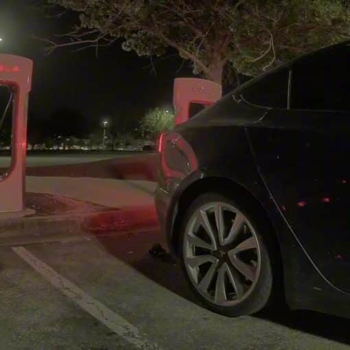 Tesla Model 3 pulling away from a Supercharger stall at night after Emergency Drive Away activation