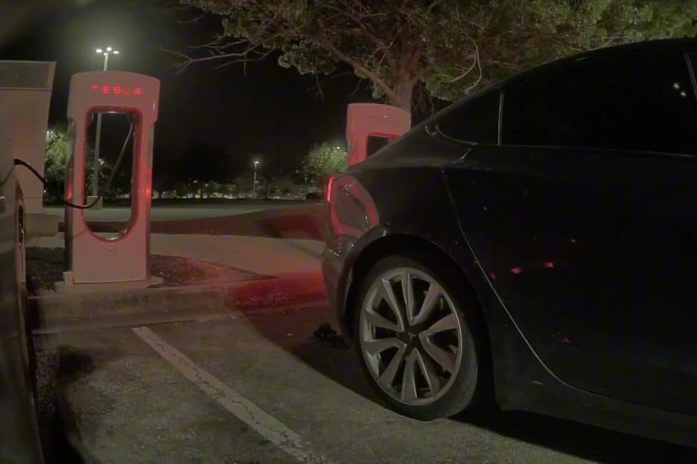 Tesla Model 3 pulling away from a Supercharger stall at night after Emergency Drive Away activation