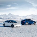 White Tesla Model 3 and blue Model Y parked on snow in front of mountains